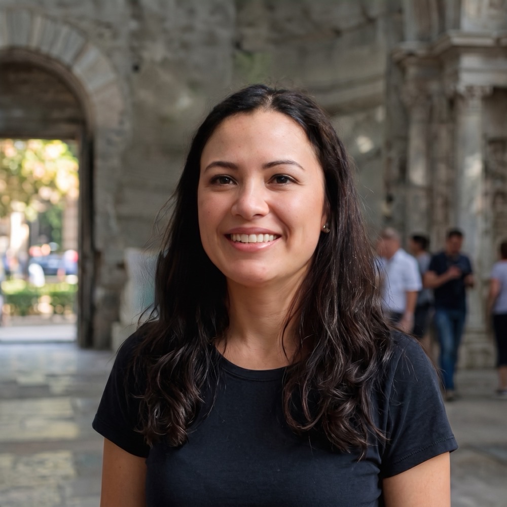 Mia Tremblay, photographed outdoors in daylight under a stone archway.